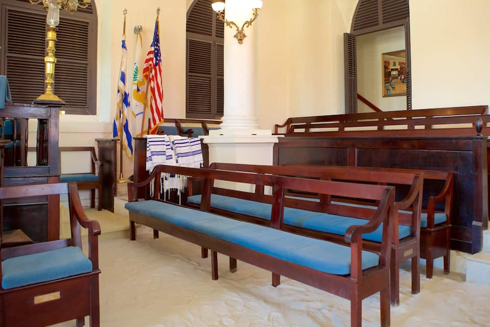 Interior de iglesia con bancas de madera, un atril y banderas.