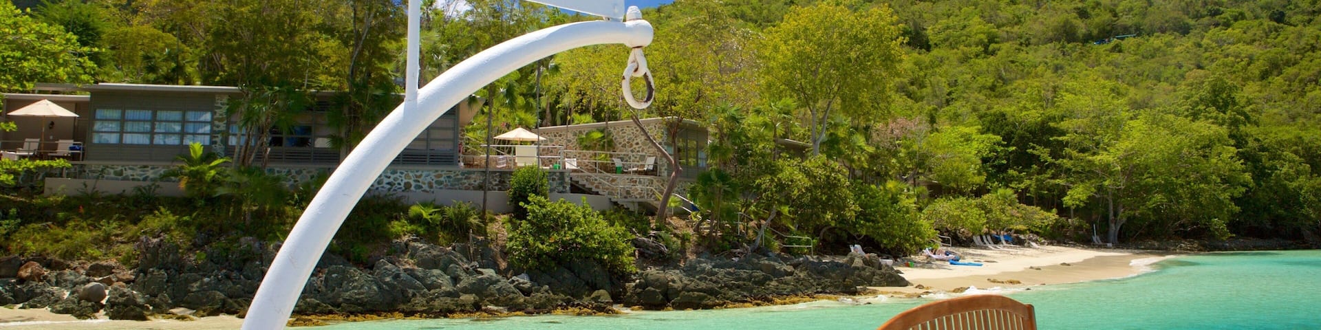 Una playa con aguas turquesas cristalinas, un banco de madera y un letrero que dice "Caneel Bay".