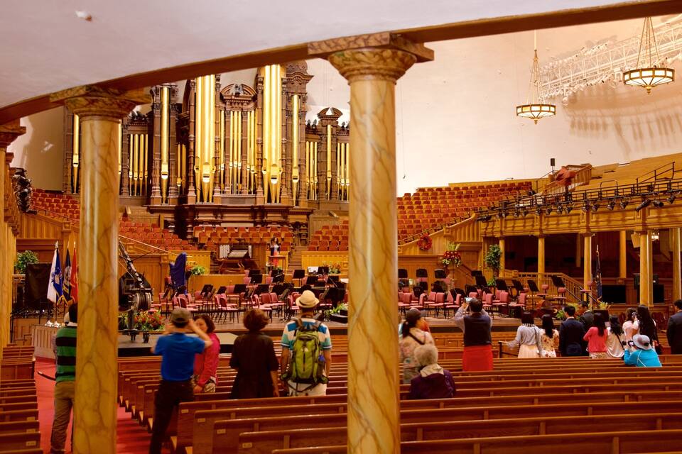A church interior with a large organ, wooden pews, and a choir area.