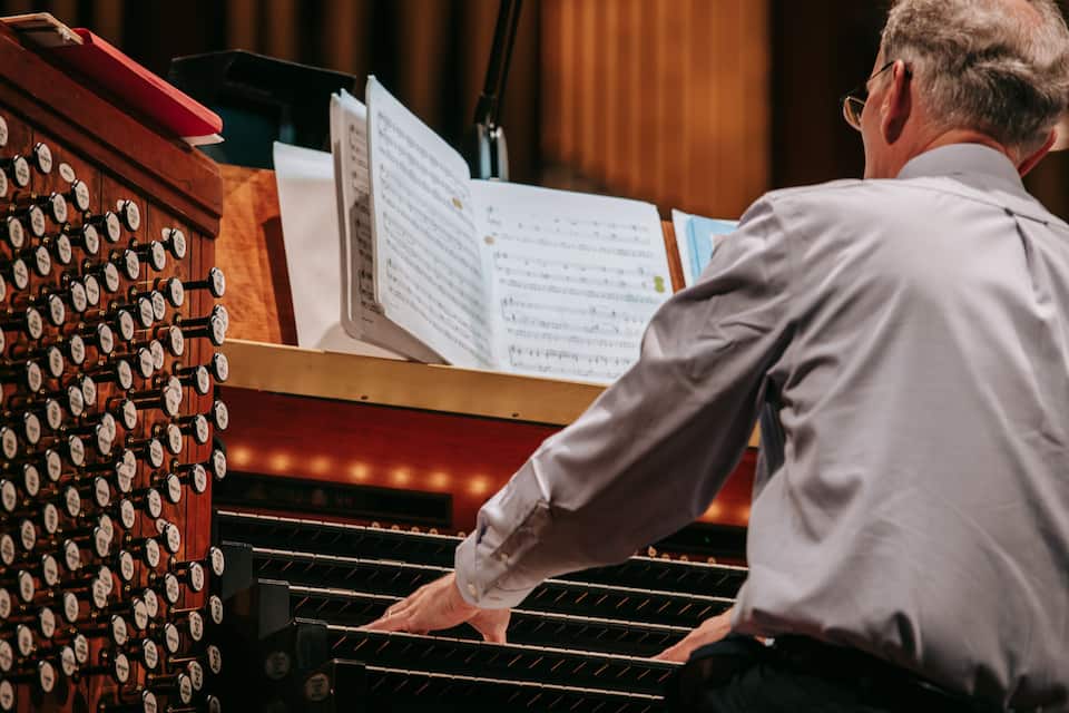 A man playing a grand piano with sheet music in front of him.