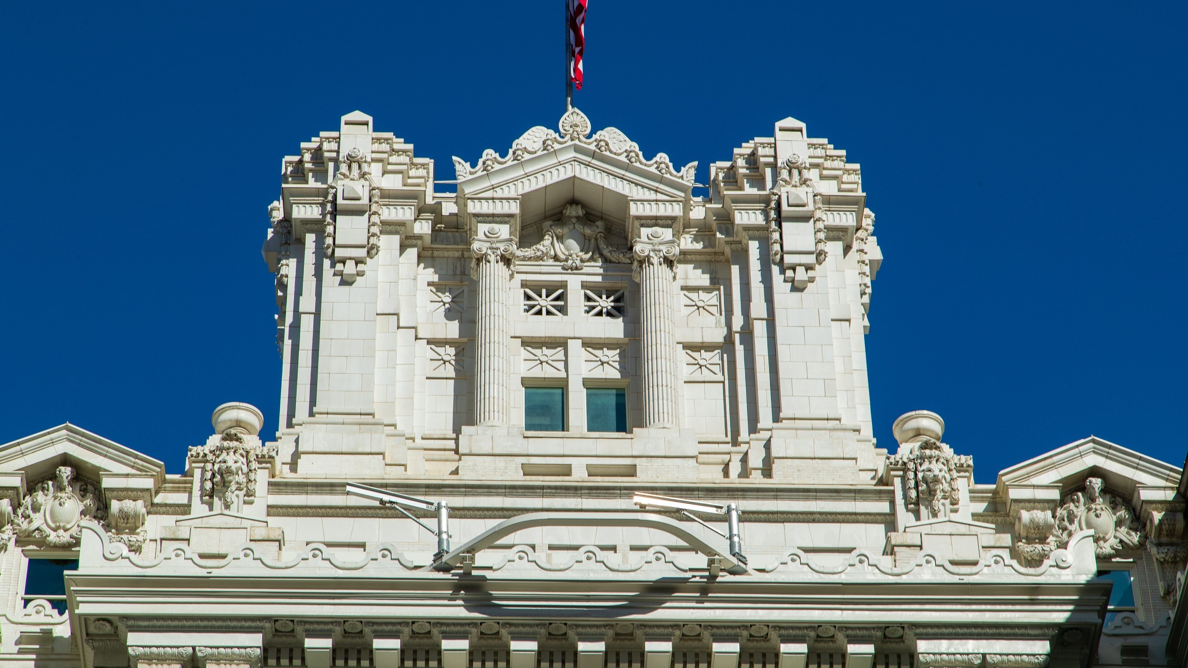 A grand building with ornate architectural details, including a large central window and statues on either side.