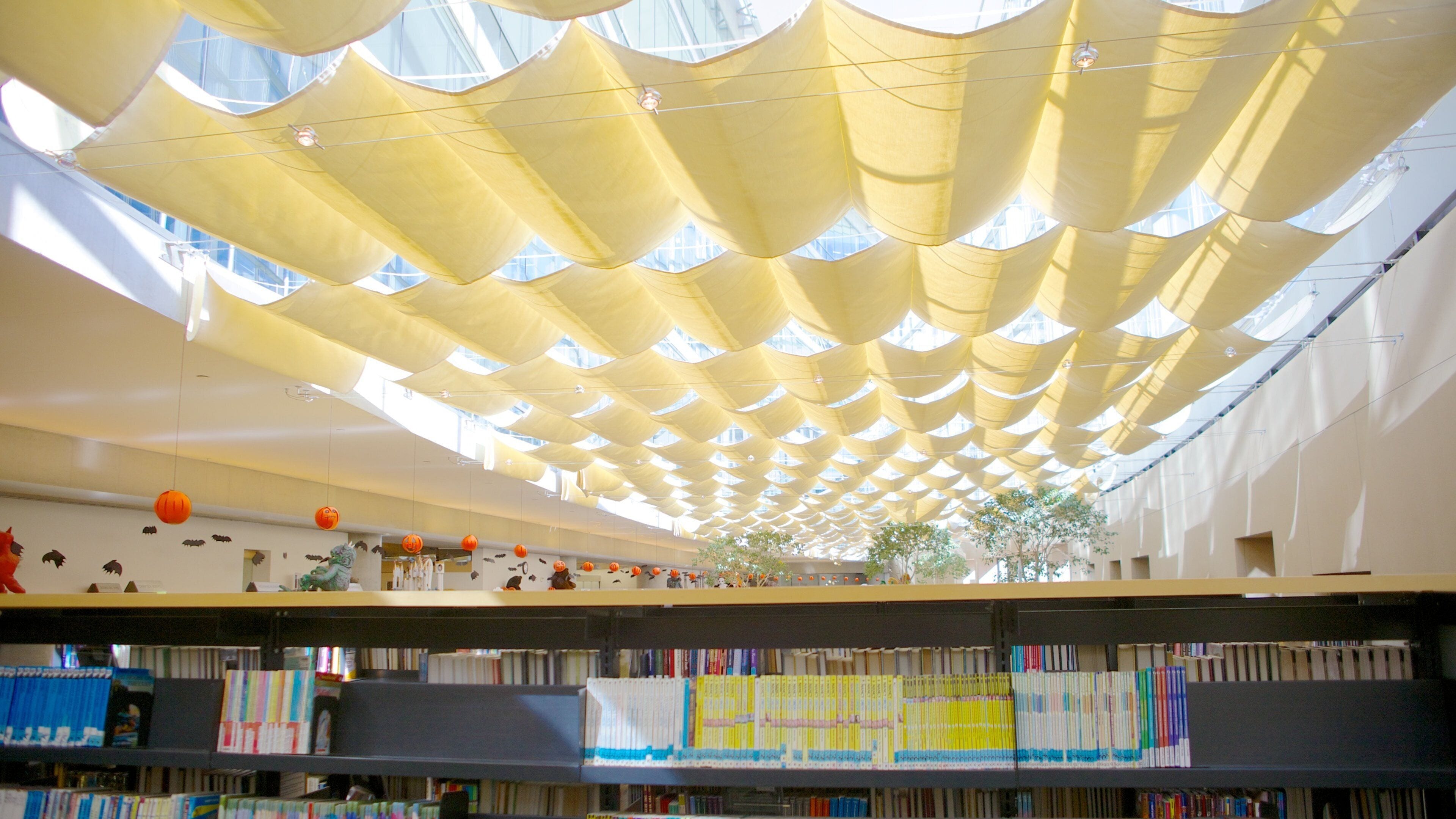 A library with a unique ceiling design and bookshelves filled with books.