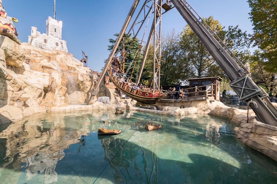Uma grande roda gigante, uma estrutura que lembra um castelo, e um corpo d'água com barcos.