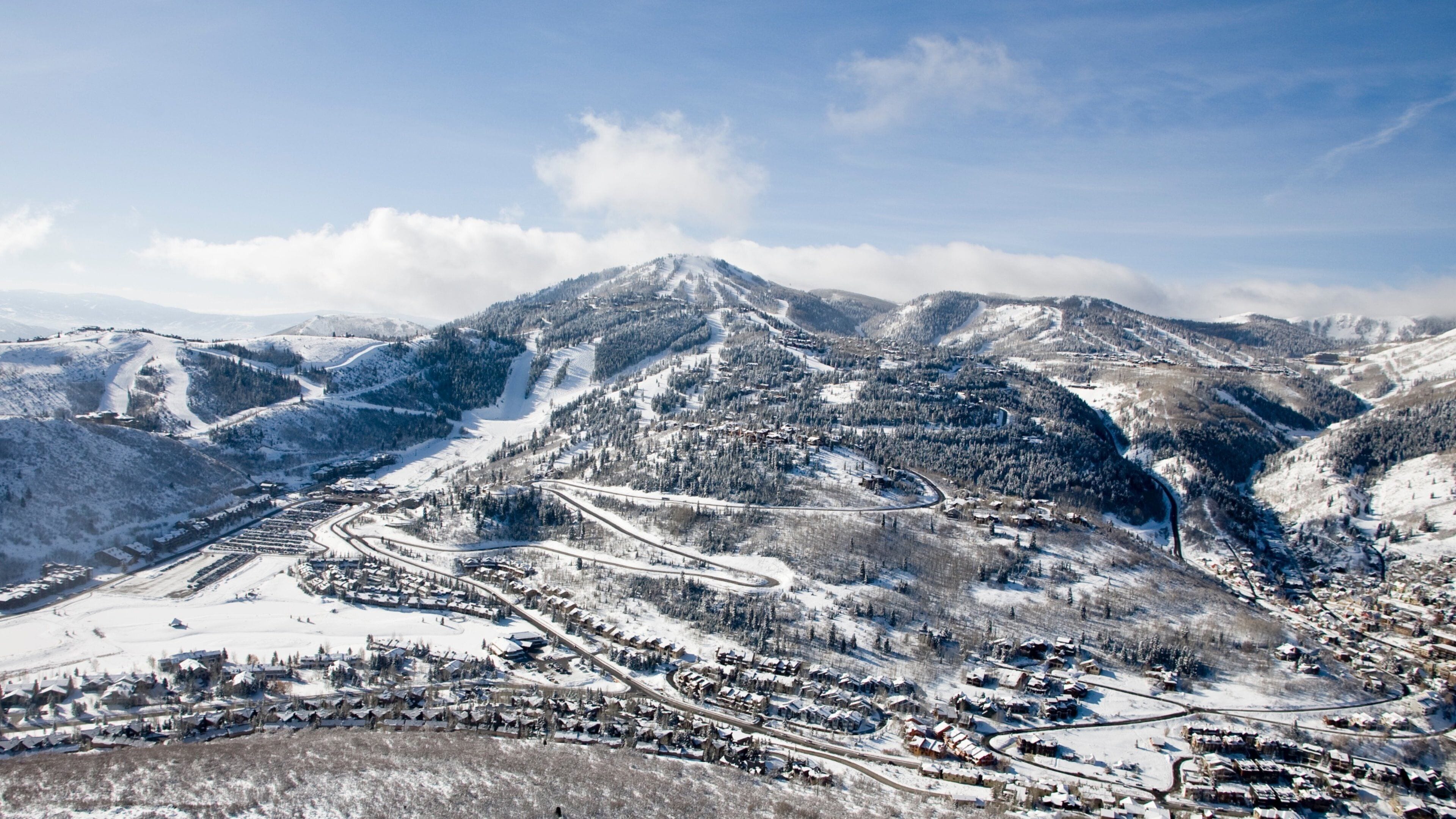 A snow-covered mountain range with ski slopes and a small town at its base.