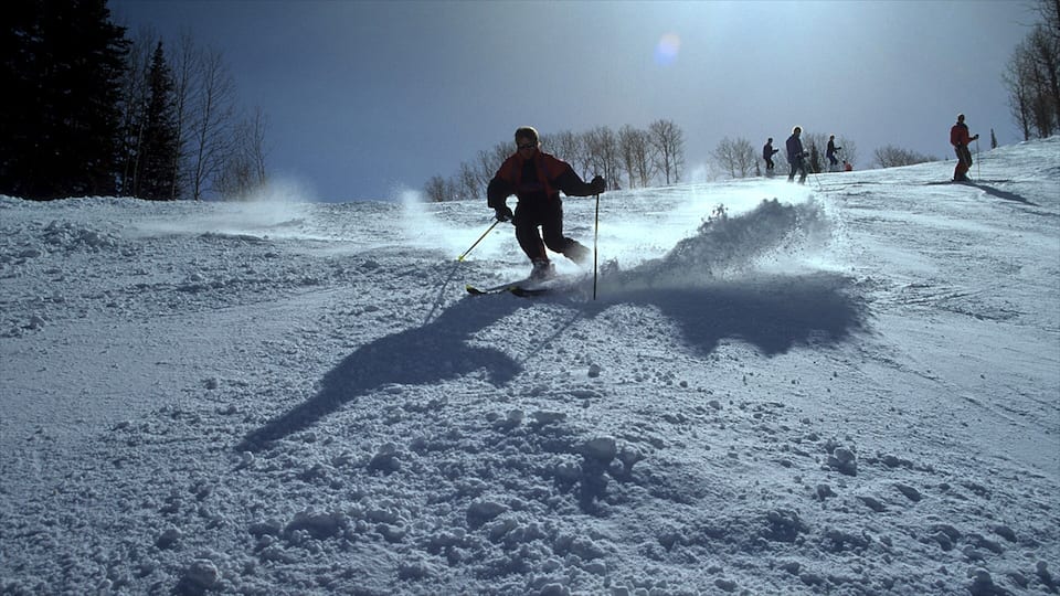 Une piste de ski enneigée, avec des skieurs qui dévalent la pente.