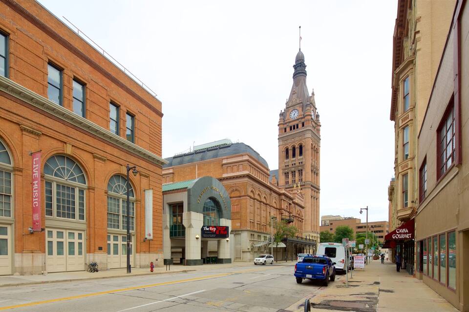 A street with a large brick building, a clock tower, and a sign for 'The Rep' restaurant.