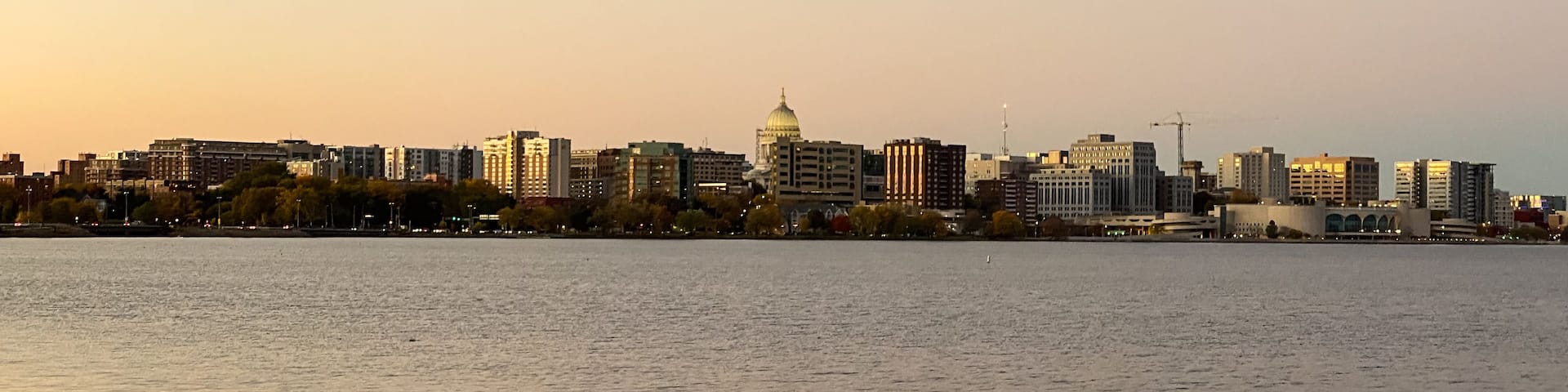 A city skyline at sunset with a large domed building in the center.