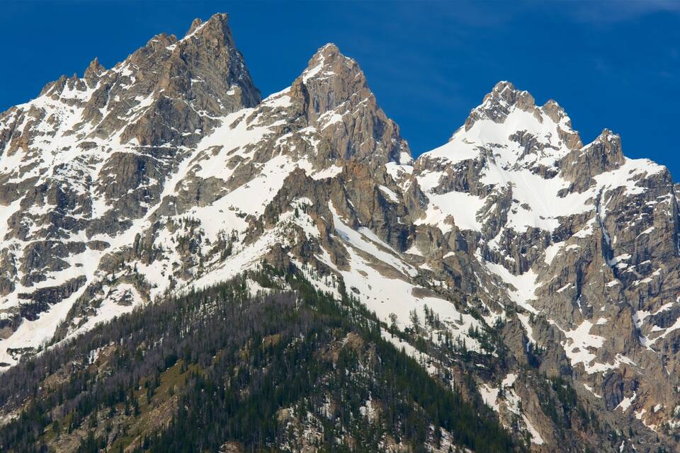 A rugged mountain range with sharp peaks and patches of snow.