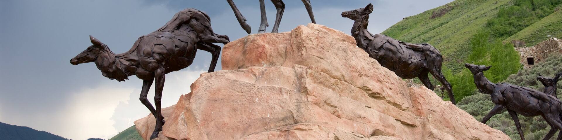 A sculpture of deer on a rock formation with a mountainous landscape in the background.