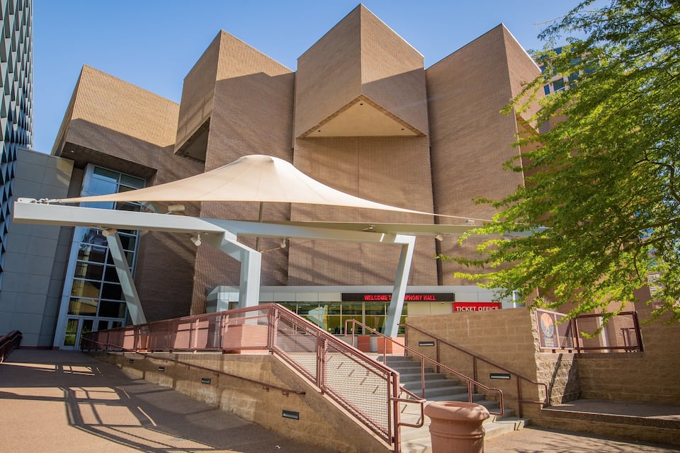 A modern building with a unique geometric facade, a ticket office, and a staircase leading to the entrance.