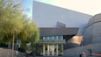 The exterior of the Reina Science Center with a modern architectural design, featuring a large glass entrance and a tree in the foreground.