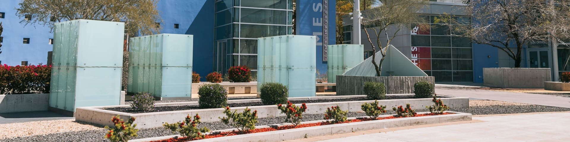 A modern building with a blue facade and a sail-like structure.