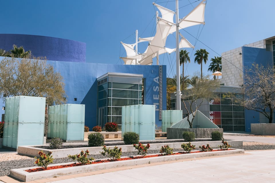 A modern building with a blue facade and a sail-like structure.