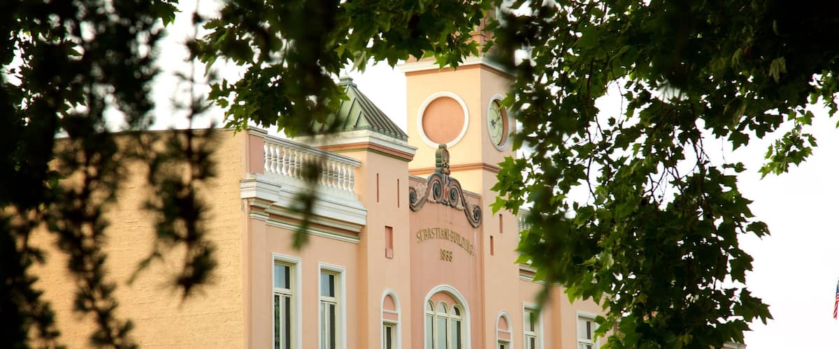 The exterior of the Sebastian Building, a pink building with a clock tower and arched windows.