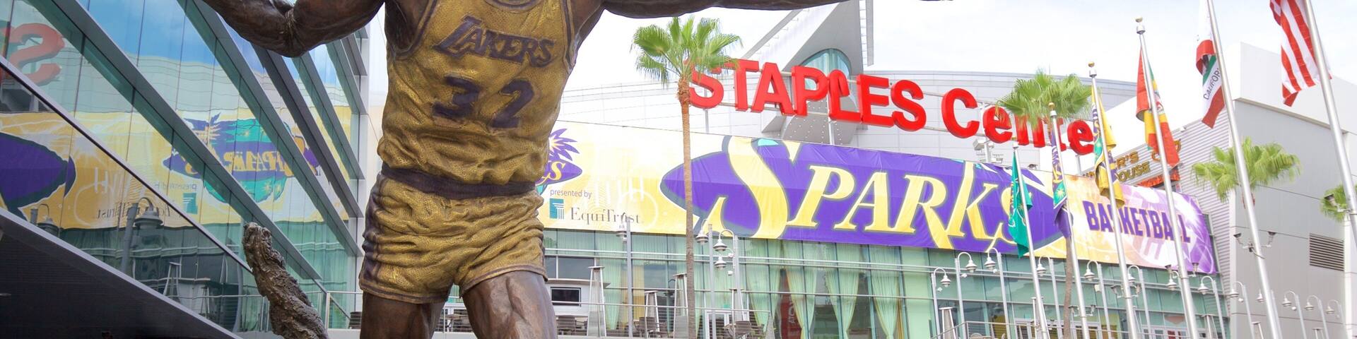 A statue of a basketball player in a yellow jersey with the number 32, pointing to the Staples Center.
