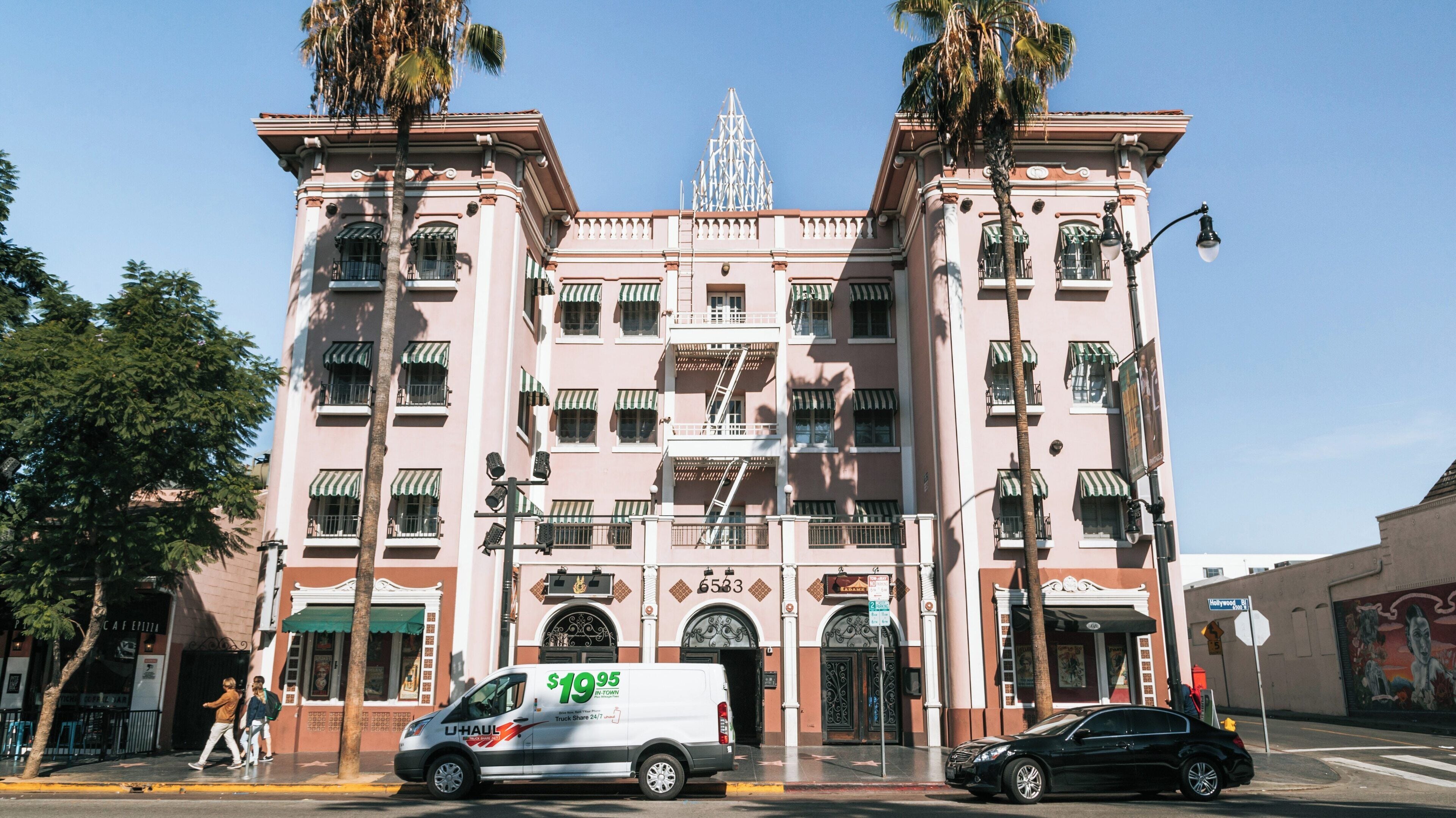 Strolling past historical buildings and palm trees on Hollywood Walk of Fame in Los Angeles during a sunny day
