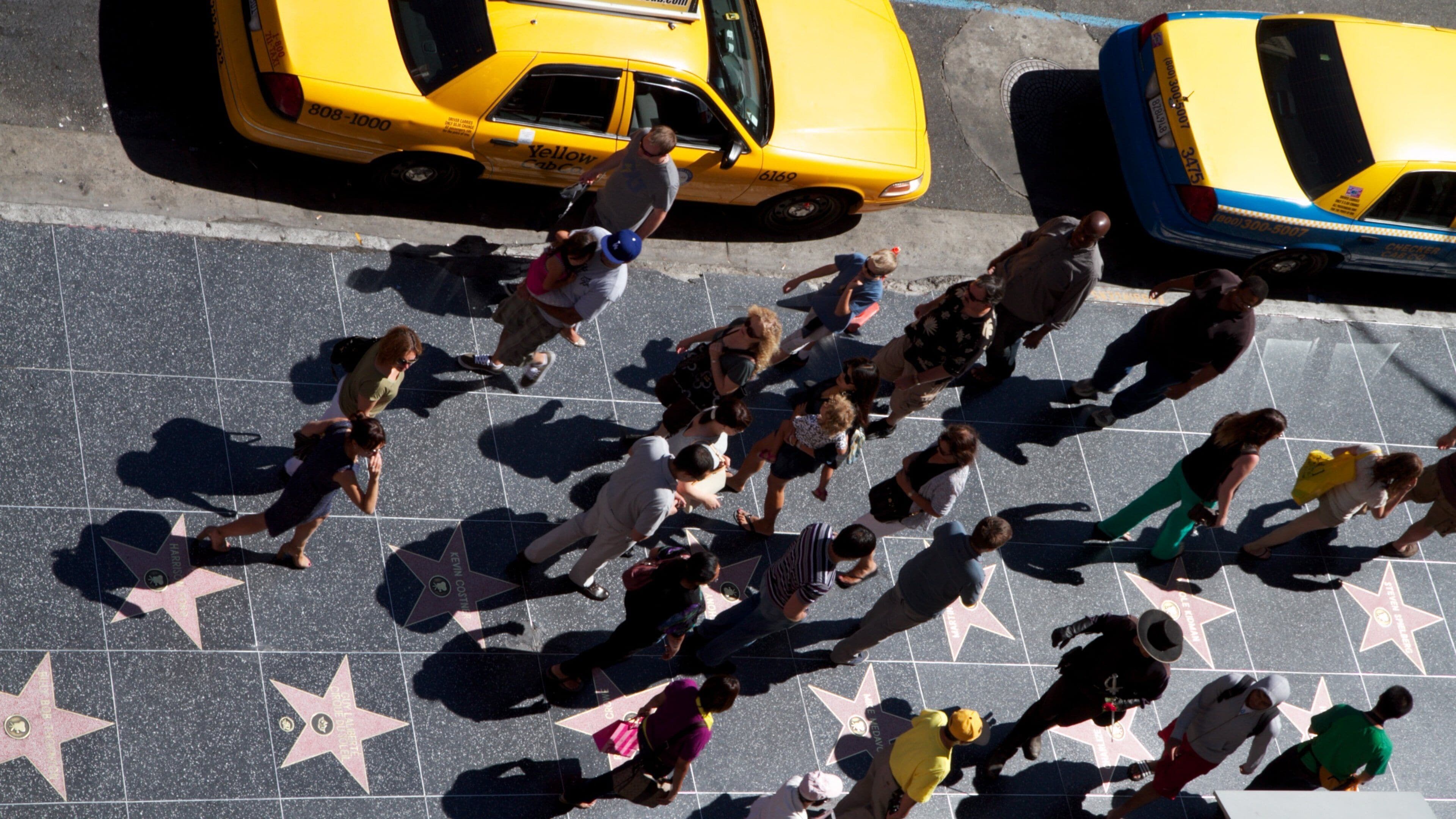 Crowds gather on Hollywood Walk of Fame with yellow taxis in Los Angeles, California