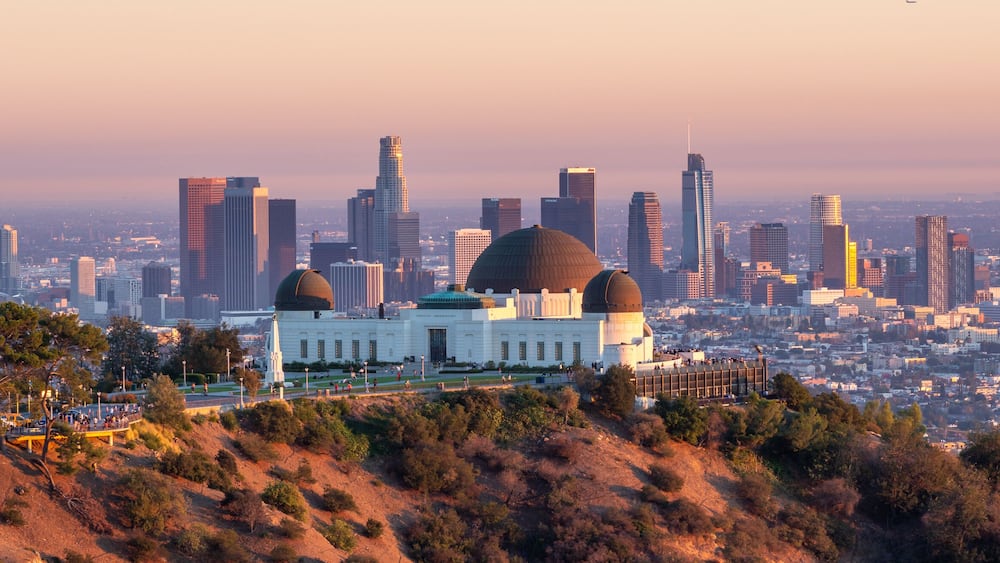 A cityscape with a prominent domed building surrounded by a hilly landscape and a dense urban skyline.