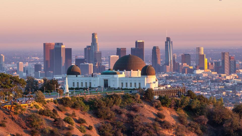 A cityscape with a prominent domed building surrounded by a hilly landscape and a dense urban skyline.
