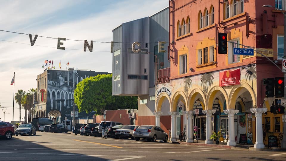A street with a large sign spelling "VEN" and a building with a sign for "El Huachique Peruvian Cuisine".