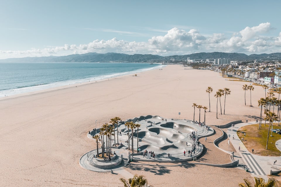 Una playa con un parque para patinadores y palmeras.