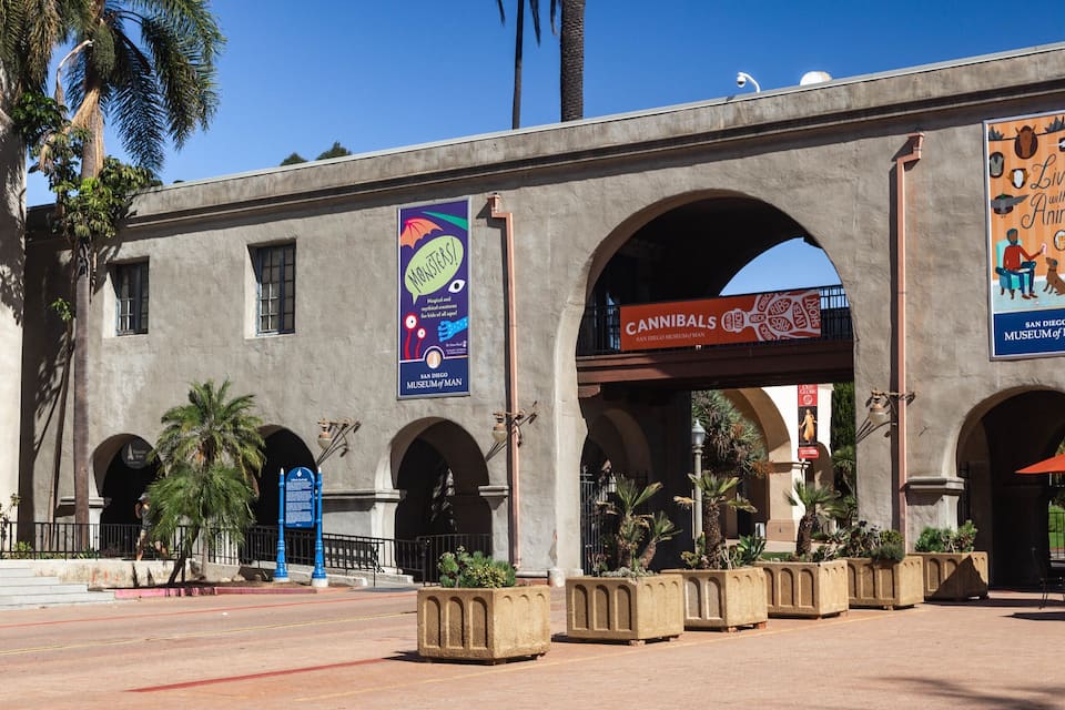 A building with multiple arches and banners advertising the San Diego Museum of Man.