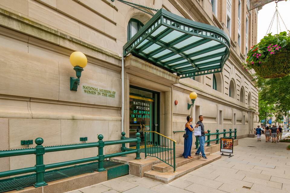 The entrance to the National Museum of Women in the Arts, featuring a green awning and a yellow street lamp.