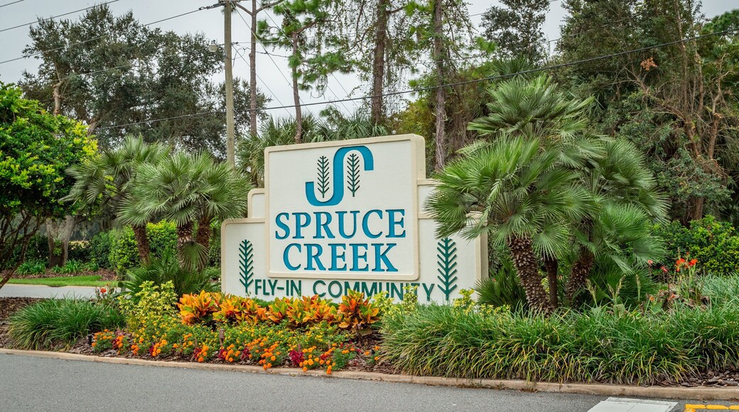 Spruce Creek Country Club featuring signage and a garden