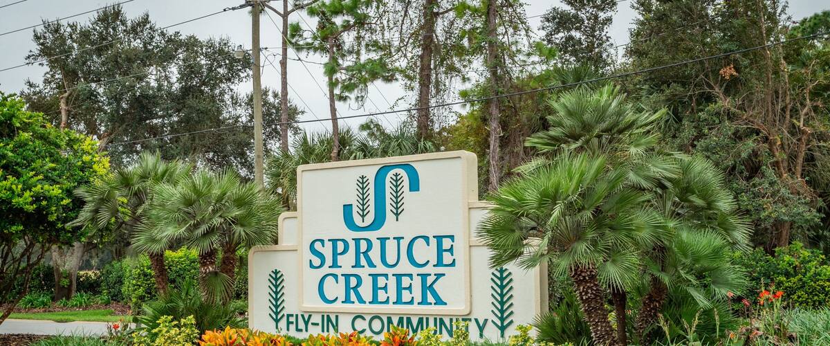 Spruce Creek Country Club featuring signage and a garden