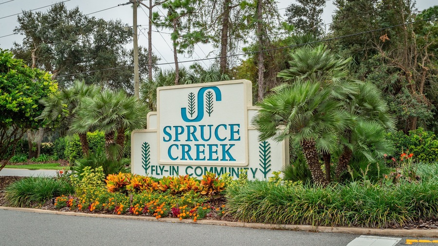 Spruce Creek Country Club featuring signage and a garden