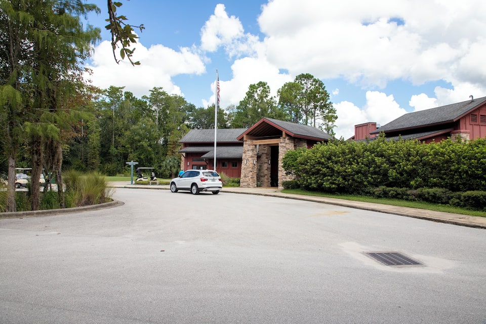 A building with a stone facade and a red roof, surrounded by greenery and a clear sky.