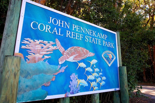 Un panneau indiquant l’entrée du parc d’État de la barrière de corail John Pennekamp, avec une illustration représentant une tortue et la vie marine.