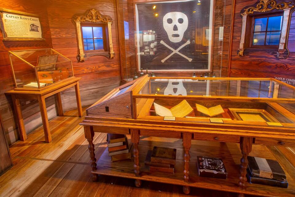 A wooden chest with a skull and crossbones, surrounded by glass display cases with documents.