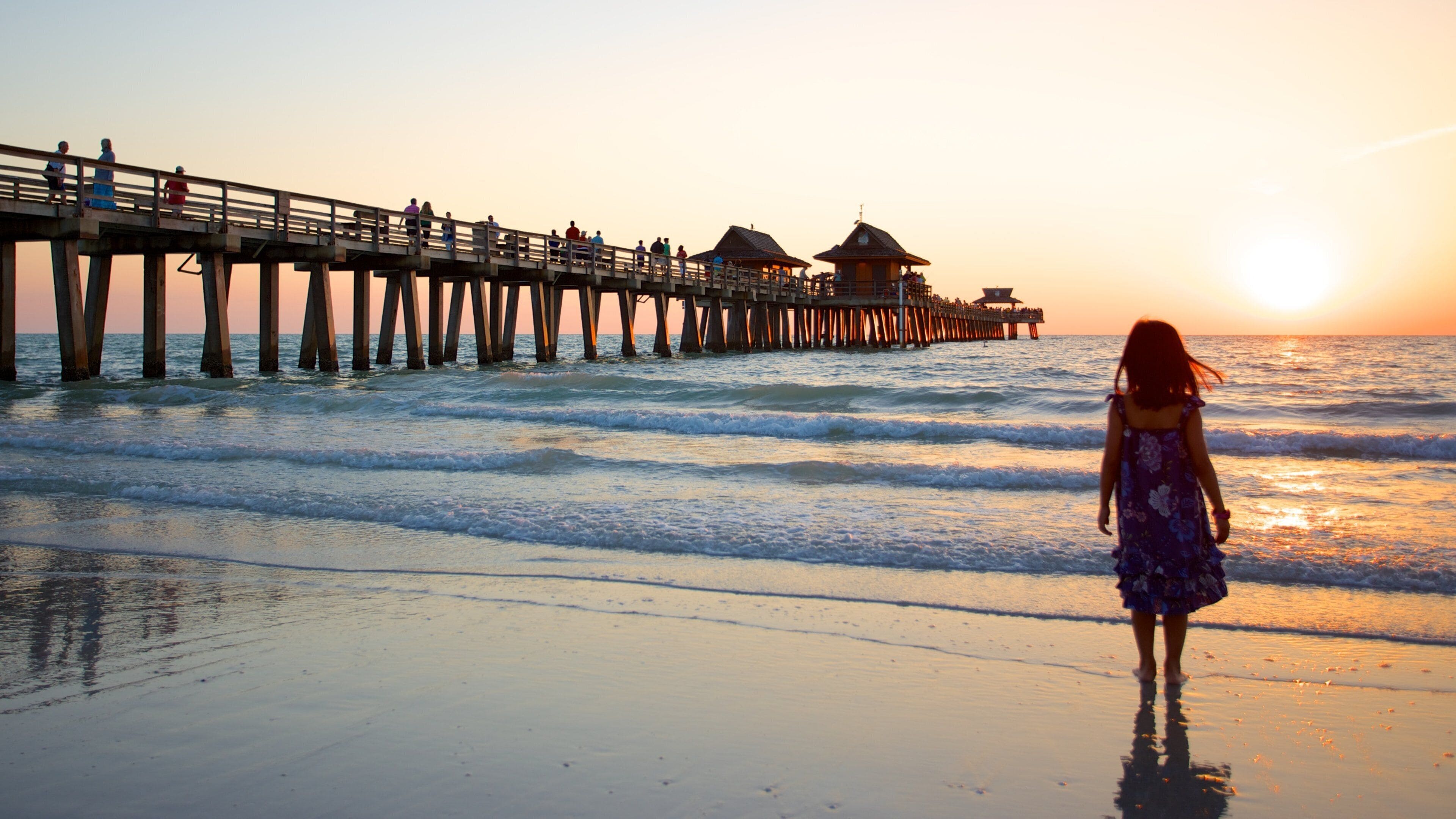 Naples Pier showing a sunset and a sandy beach as well as an individual child
