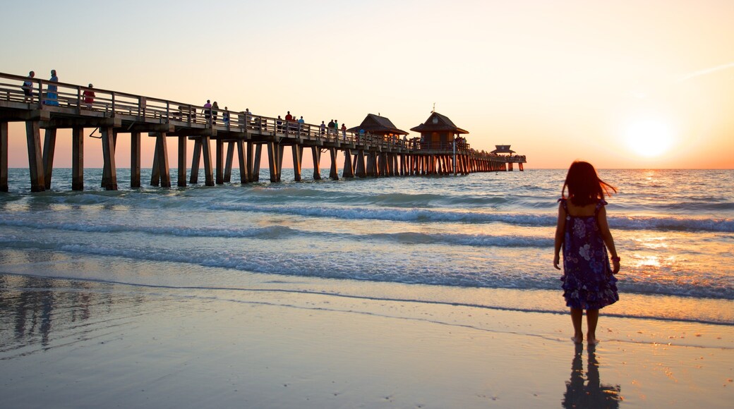 Naples Pier showing a sunset and a sandy beach as well as an individual child