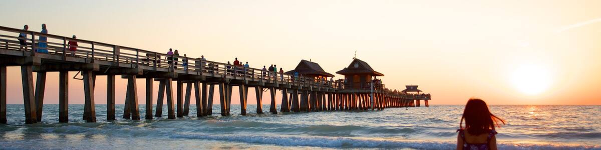 Naples Pier showing a sunset and a sandy beach as well as an individual child