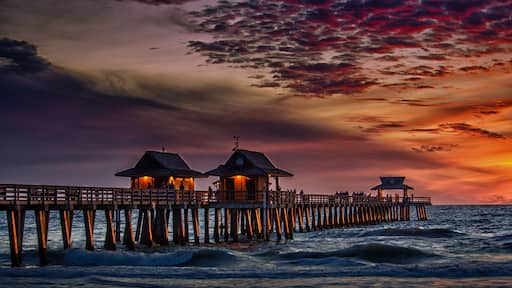 Un molo con due strutture illuminate e un punto panoramico che si estende sull'oceano al tramonto.