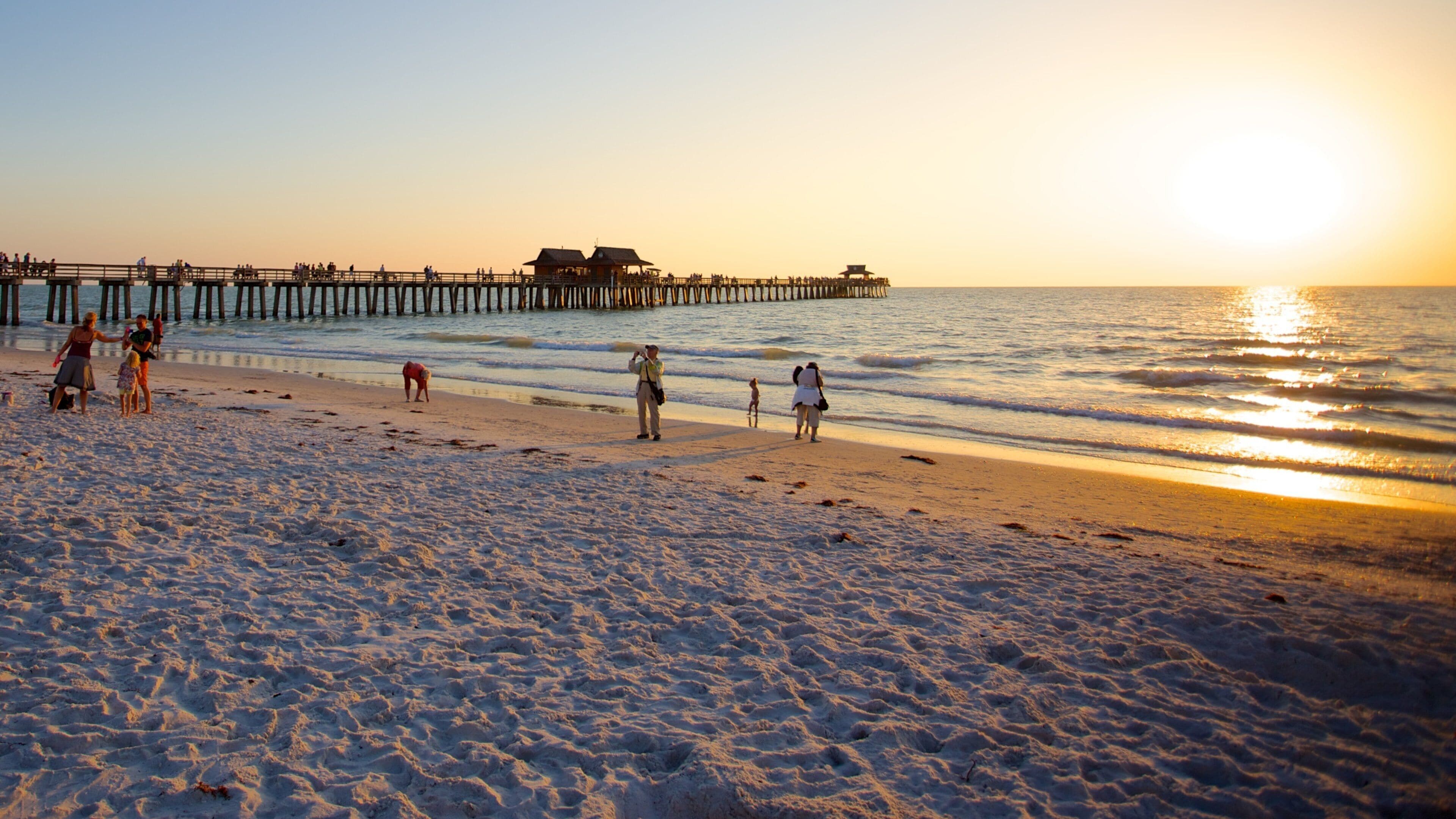Naples Pier which includes a sunset and a sandy beach
