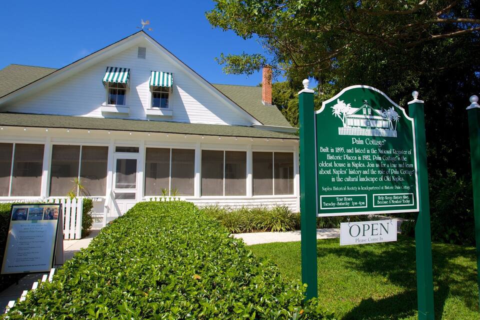 A historic house with a green sign in front.