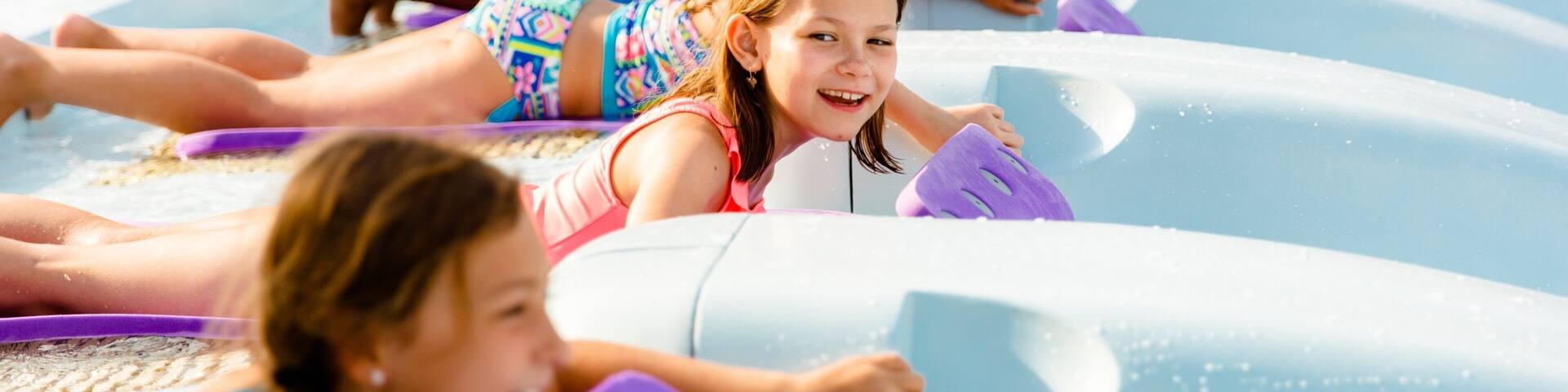 Children lying on water slides in a water park.
