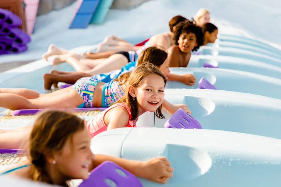 Children lying on water slides in a water park.