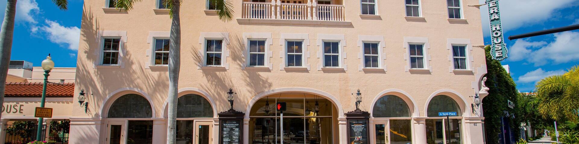 A two-story building with a balcony, arched windows, and a sign that reads "Open".