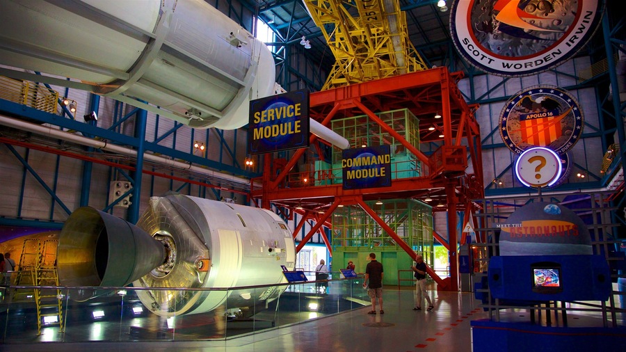 A space shuttle on display in a museum with signs reading "Service Module" and "Command Module".
