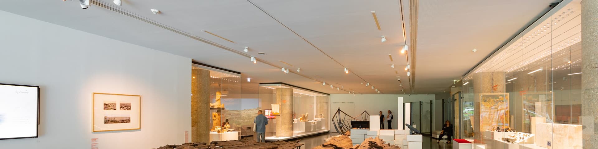 An indoor art gallery with a large wooden sculpture and glass display cases.