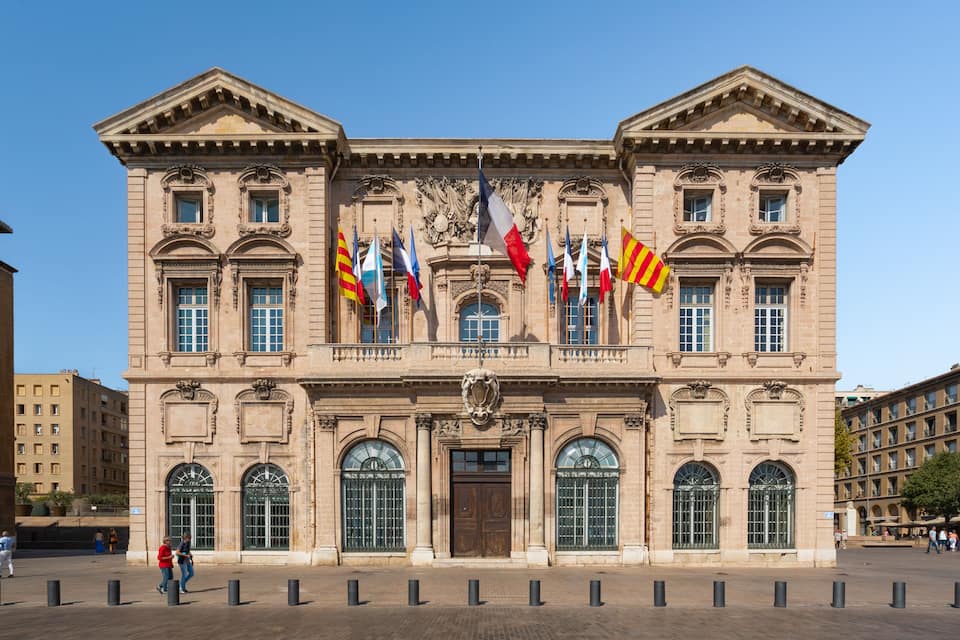 A historic building with ornate architecture, multiple flags, and a central entrance.