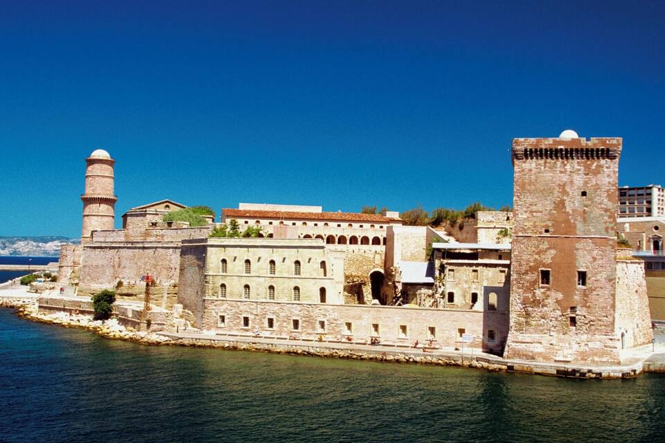 Une forteresse côtière historique, dotée d’une tour imposante et d’un grand bâtiment aux fenêtres en arc.