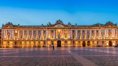 Fachada del Museo del Louvre al anochecer, con arquitectura clásica y la emblemática entrada en forma de pirámide de vidrio.