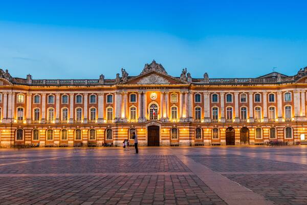 La façade du musée du Louvre au crépuscule, avec son architecture classique et l’emblématique pyramide de verre qui sert d’entrée.