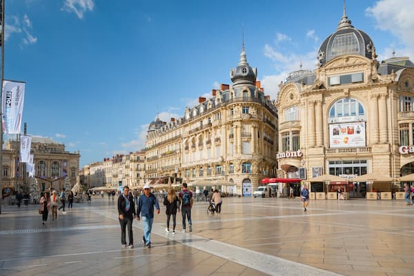 Une place animée, bordée de bâtiments richement décorés, notamment un cinéma « Gaumont » bien en vue et un restaurant « Popeyes ».