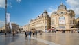 A bustling square with ornate buildings, including a prominent 'Gaumont' cinema and a 'Popeyes' restaurant.